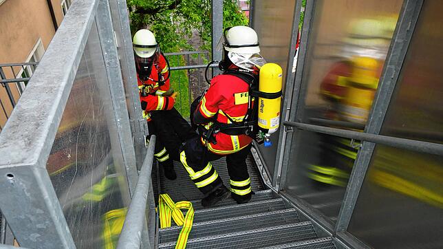 Zwei Einsatzkräfte der Feuerwehr tragen bei der Probe eine bewusstlose Person aus dem Gebäude der Zeppelin-Realschule. Für den ...