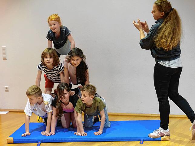 Die Kinder lernen Techniken, wie sie gemeinsam Menschenpyramiden bauen können. Klassenlehrerin Katharina Grieshaber gibt Tipps und Applaus.