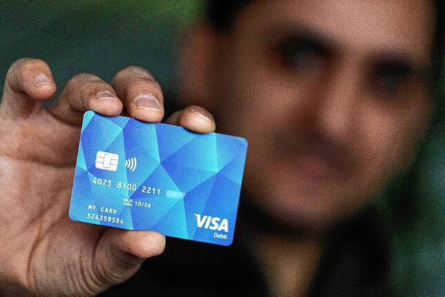 Symbolbild: Baden-Württemberg, Offenburg: Ein Geflüchteter hält eine Debitcard in der Hand.