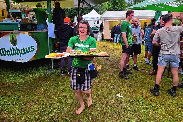 Mit guter Laune beim Bedienen: Martina Furtwängler hat ihre Schuhe nach dem Regenunwetter kurzer Hand zur Seite gelegt.