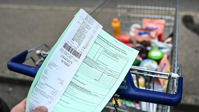 Ein Schweizer Kunde vor dem Einkaufswagen hält einen Ausfuhrschein in der Hand (Symbolbild). Die Wertfreigrenze wird im neuen Jahr halbiert.