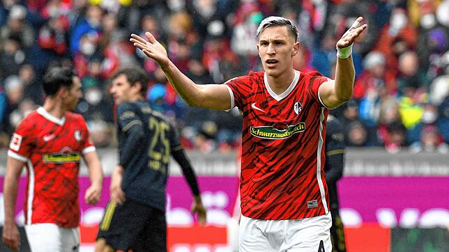 Da ist doch einer zu viel: Freiburgs Nico Schlotterbeck ist von der Anzahl der Münchner Kicker auf dem Feld irritiert.