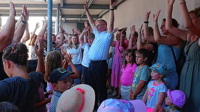 Nach dem Abschiedsgottesdienst singt Pfarrer Sickinger auf dem Kirchplatz mit Erzieherinnen und Kindern der Kitas der Seelsorgeeinheit ...