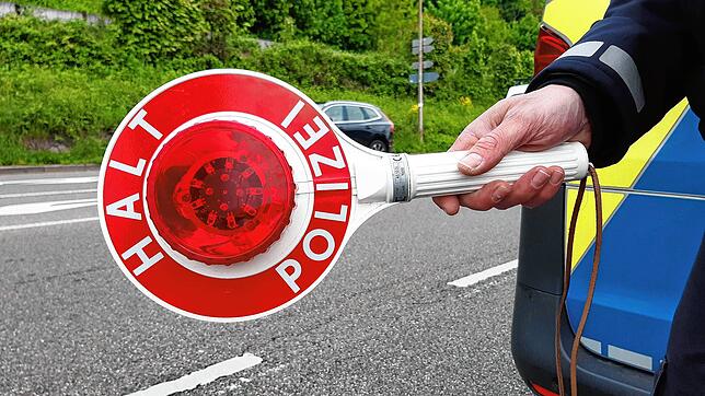 Ein Polizist hält eine Kelle, um das Anhalten zu signalisieren. (Symbolbild)