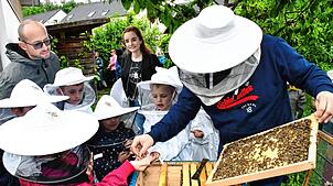 Unterricht einmal ganz praxisnah: Imker Bastian Engel erklärt den Kindern der „Bienenklasse“ seine Bienenstöcke. Bild: Heinz Vollmar