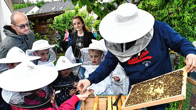 Unterricht einmal ganz praxisnah: Imker Bastian Engel erklärt den Kindern der „Bienenklasse“ seine Bienenstöcke. Bild: Heinz Vollmar