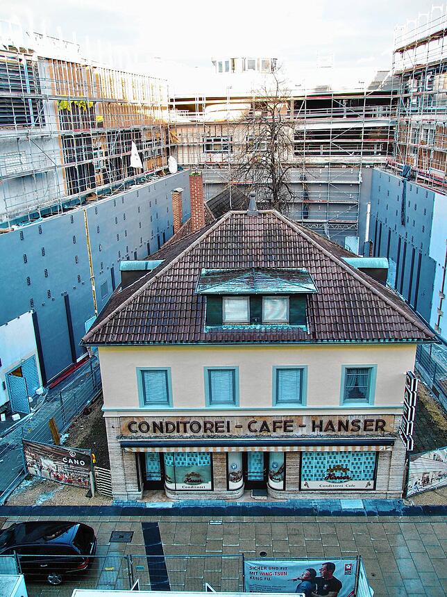 Von dem Gebäudeteilen des neuen Einkaufszentrums Cano in die Zange genommen, so wirkt das kleine Café Hanser in der August-Ruf-Straße. ...