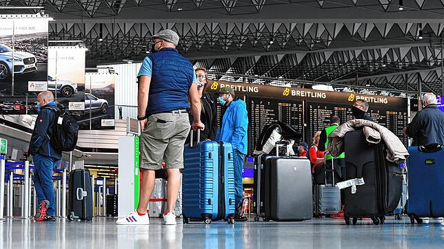 Flugreisende stehen in Terminal 1 des Frankfurter Flughafens am Check-in-Schalter von Air Canada an. Die Reisewarnung für 27 europäische ...