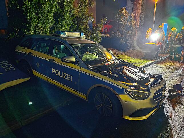 Ein Schweinwerfer der Feuerwehr taucht das zerstörte Polizei-Auto in grelles Licht.