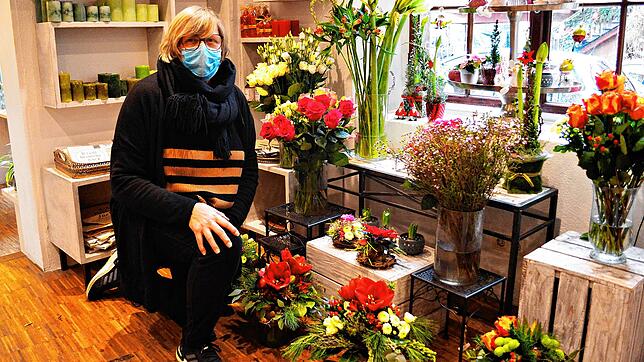 Angela Messerle sitzt vor den Blumengestecken und -sträußen in ihrem Laden in der Steigstraße in Meersburg. &bdquo;Um die Blumen ist es ...