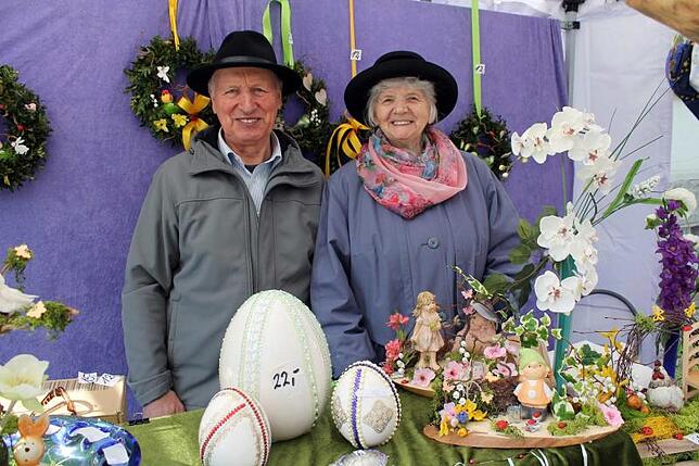 Einen bunten Osterstand mit vielen selbstgefertigten Ostergeschenken, darunter Blumen- und Figurengebinde, bemalte Ostereier in allen ...