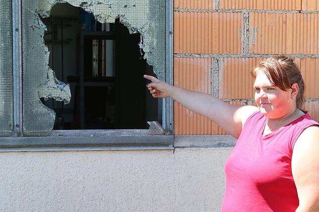 Klara Braun deutet auf eines der Fenster, die an der Gewerbehalle des Fuhr- und Baggerunternehmens Kreuzer zertrümmert wurden.
