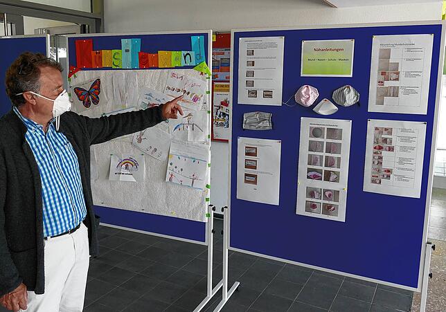 Schulleiter Klaus Flockerzie zeigt auf einer Infotafel die Nähanleitungen für Alltagsmasken, wie sie in der schuleigenen Nähstube ...