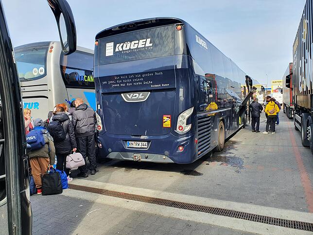 Einer der Kögelbusse neben einem anderen mit polnischem Kennzeichen, vor dem sich eine Menschenschlage gebildet hat