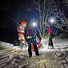 Mit dem Wannenschlitten transportieren Bergretter eine Patientin mit Kreislaufproblemen durch den Tiefschnee.