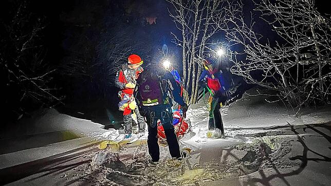 Mit dem Wannenschlitten transportieren Bergretter eine Patientin mit Kreislaufproblemen durch den Tiefschnee.
