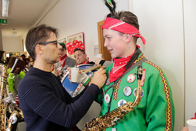 Redaktionsleiter Norbert Trippl heftet den Musikern der Stadtharmonie beim Redaktionsbesuch am Donnerstag einen SÜDKURIER-Fasnetbändel an.