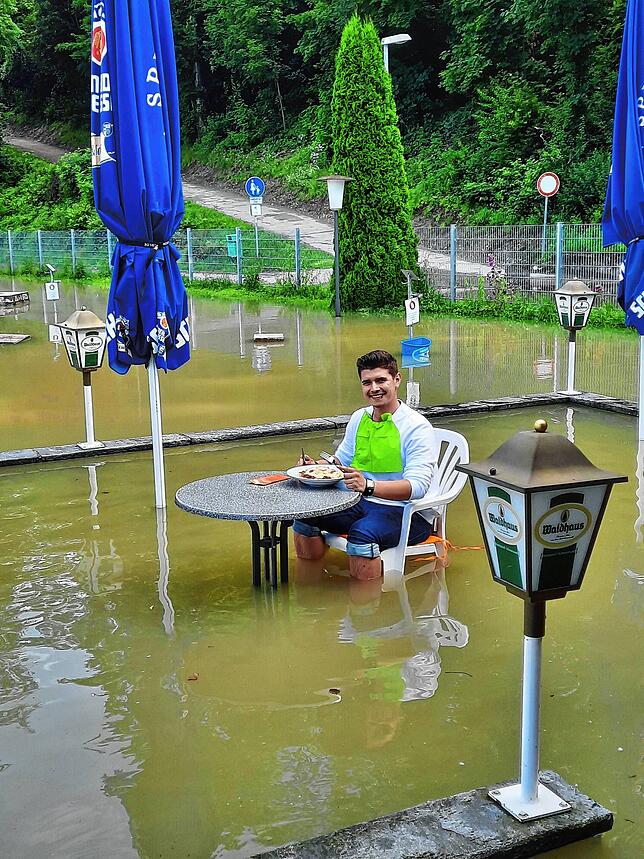Land unter auf dem Minigolfplatz in Waldshut: Kiosk-Mitarbeiter Marcel Rech lässt sich sein Mittagessen trotz Überschwemmung schmecken. ...