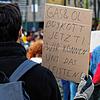 Ein Teilnehmer hält bei einer Demonstration in Köln gegen den Krieg in der Ukraine ein Schild mit Aufschrift &bdquo;Gas und Öl Boykott ...