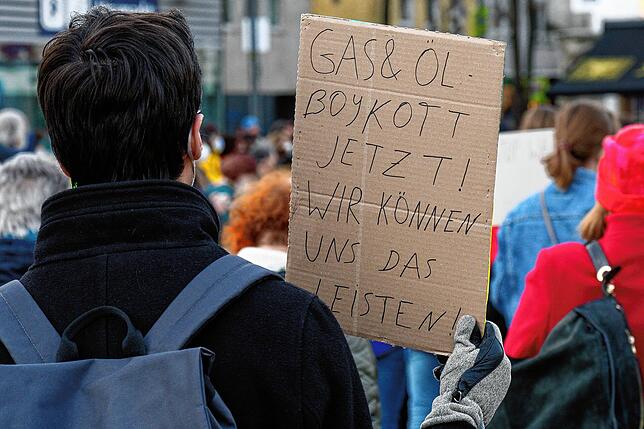 Ein Teilnehmer hält bei einer Demonstration in Köln gegen den Krieg in der Ukraine ein Schild mit Aufschrift „Gas und Öl Boykott ...