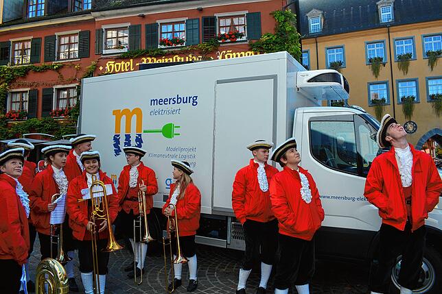 Mitglieder der Knabenmusik schauen vor dem neuen vollelektrischen Liefer-Lastwagen den davonschwebenden Luftballons nach, die das ...
