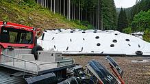 Der Pistenbully steht bereit um den Schnee des Schwarzwaldgletschers, der noch unter der Folie wartet, auf die Schanze und den Auslauf ...
