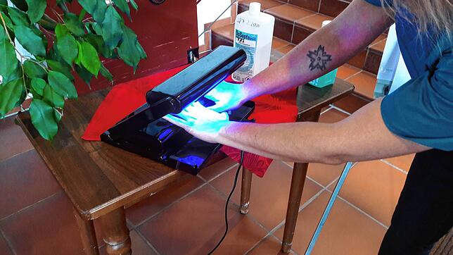 Eine UV-Lampe zeigt, ob die Hände richtig desinfiziert worden sind: Wenn dunkle Flecken zu sehen sind, gibt es Benetzunglücken, an ...