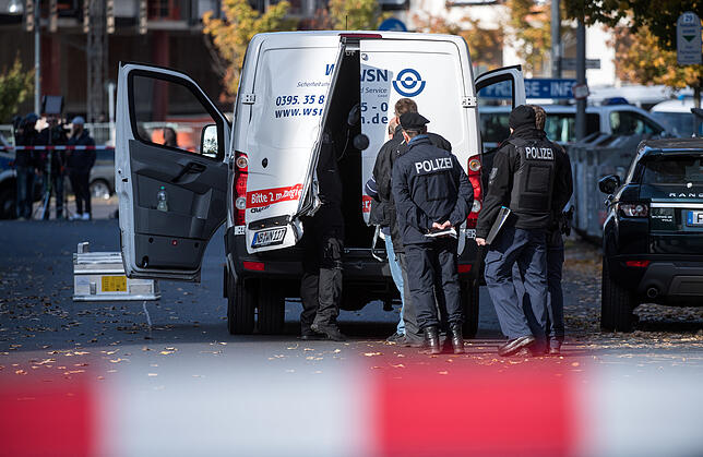 dpa-Story - Clan-Kriminalität in Berlin Polizeibeamte stehen an einem Geldtransporter mit aufgebrochenen Türen in Mitte. Mehrere Maskierte hatten das Fahrzeug in der Nähe des ...
