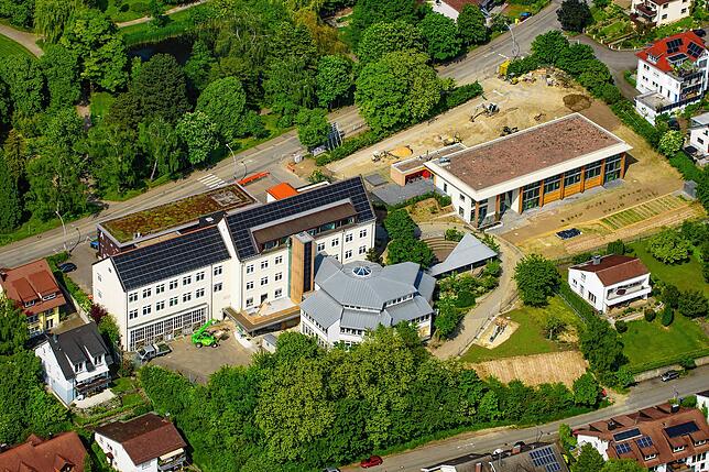 Diese Luftbildaufnahme entstand im Mai 2023: links die Schule, rechts die neue Turnhalle.