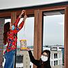 Auszubildende Lisa Kretzer (links) bringt mit Verwaltungskraft Madlene Tavit die erste Laterne an der Fensterfront des Neuen Rathauses an.