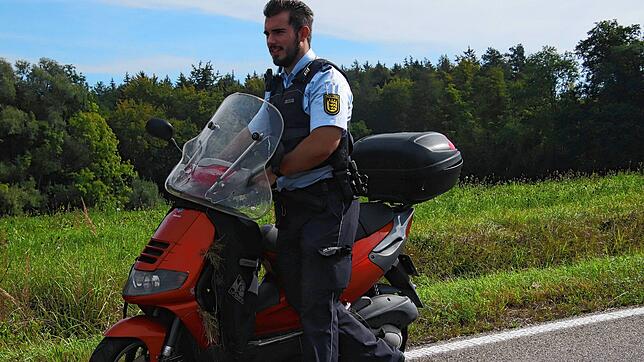 Ein Polizist schiebt nach einem Unfall an der Ausfahrt Nußdorf ein Motorrad von der Straße.