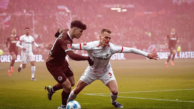 St. Paulis Noah Weißhaupt (l) und Freiburgs Philipp Lienhart im Kampf um den Ball.