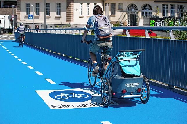 Ein Radfahrer mit Kinderanhänger auf der alten, 2021 eröffneten Radbrücke in Tübingen.