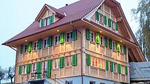 Ein Thoma Holz100-Haus mit traditioneller Ständer-Bohlen-Fassade, das moderne Technik und nachhaltige Bauweise harmonisch vereint. ...