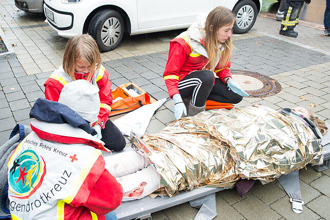 Die Kindergruppe des DRK-Ortsvereins versorgt die realitätsnah geschminkten Verletzungen der Radfahrerin.