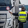 Polizisten halten Fahrzeuge an einer Grenze an.
