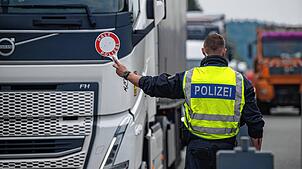 Polizisten halten Fahrzeuge an einer Grenze an.