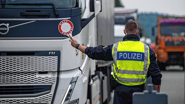 Polizisten halten Fahrzeuge an einer Grenze an.