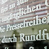 Das Wort Pressefreiheit in einem Ausschnitt des Artikels 5 des Grundgesetzes auf einer Scheibe eines Bundestags-Gebäudes ...
