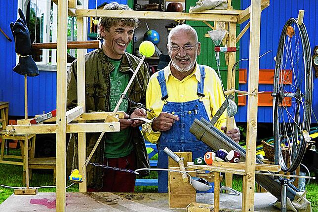 Guido Hammesfahr (links) und Peter Lustig (1937-2016) stehen bei Dreharbeiten für „Löwenzahn“ hinter einer selbstgebauten Maschine.