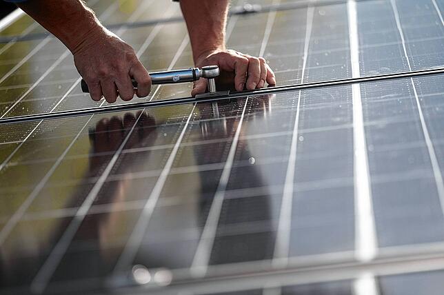 Mitarbeiter einer Firma montieren Photovoltaikmodule auf dem Dach eines Wohnhauses. Bei den Stromgestehungskosten ist nichts so günstig ...