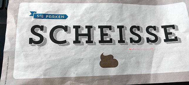 Der Zettel, der unter dem Scheibenwischer auf der Windschutzscheibe hing.