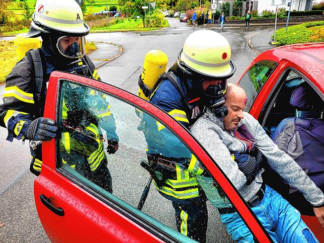 Mit Atemschutzmasken retten Feuerwehrangehörige im Rahmen der Übung einen eingeklemmten Fahrer aus seinem Auto.