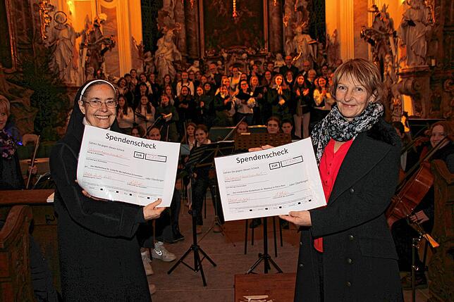Schulleiterin Heidi Linster (rechts) überreichte am Ende des Weihnachtskonzertes die symbolischen Spendenschecks aus dem Erlös des ...