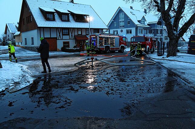 Auf der Straße neben dem niedergebrannten Gebäude schwimmen Reste der Brandnacht im Löschwasser.