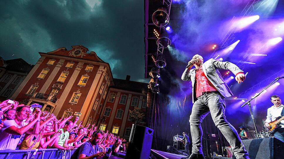 2018: Die Band Simple Minds rockt die Bühne bei den Schlossplatz Open Airs in Meersburg, während sich am Himmel die Regenwolken ...