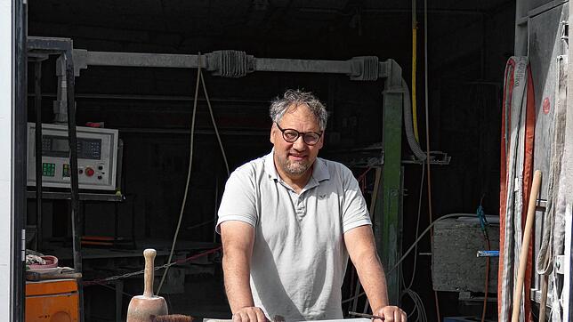 Jürgen Kübler vor seiner Werkstatt, an seinem aktuellen Werkstück, einen Sockel für ein Wegkreuz. Foto: Rotraud Opfermann