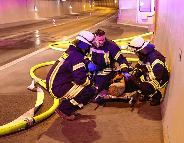Eine der fünf im Tunnel geretteten Personen, simuliert durch einen Dummy, wird von den Feuerwehrlern betreut.