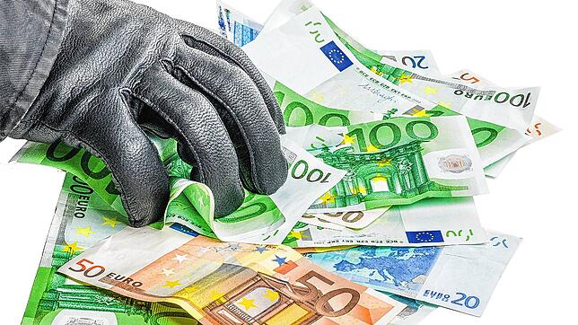 Dieb mit Lederhandschuh greift nach Geldscheinen.