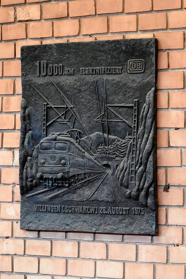 Diese Bronzetafel im Bahnhof Villingen (am Gleis 1) erinnert an die Fertigstellung des 10.000. Kilometers unter Fahrdraht der damaligen ...